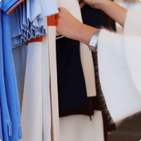 Pessoa escolhendo roupas de diferentes texturas em uma arara de loja