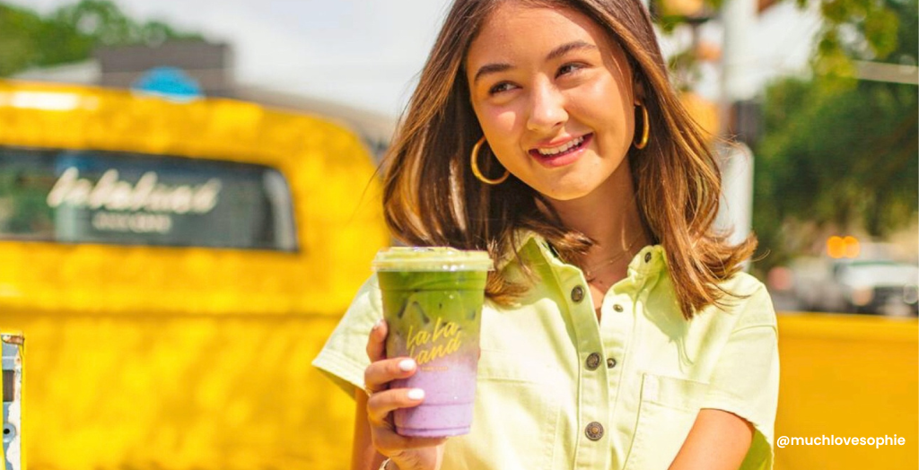 Gen Z influencer Creator @Muchlovesophie sits on a yellow truck showcasing a multicolored beverage.