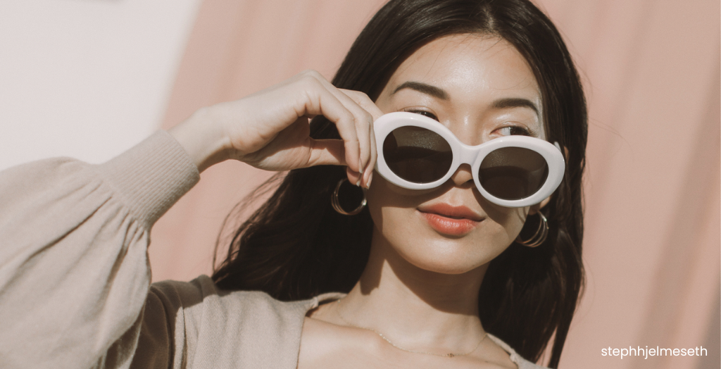 Creator @stephhjelmeseth wearing white sunglasses and hoop earrings in the sun.