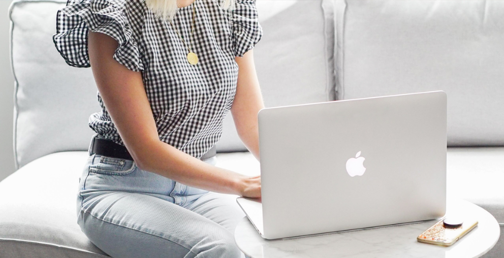 A content Creator in a frilly gingham blouse shares messages with followers on her laptop.