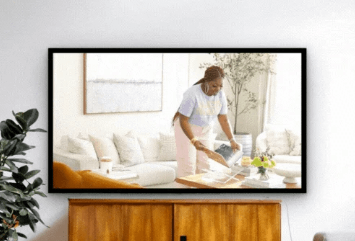 Creator on TV screen placing book on coffee table