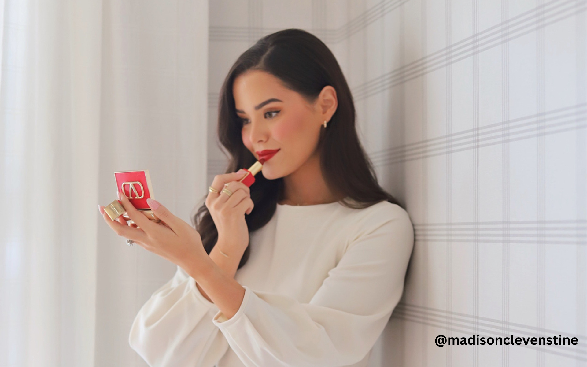  Beauty Blogger and LTK Creator @madisonclevenstine applies red lipstick.